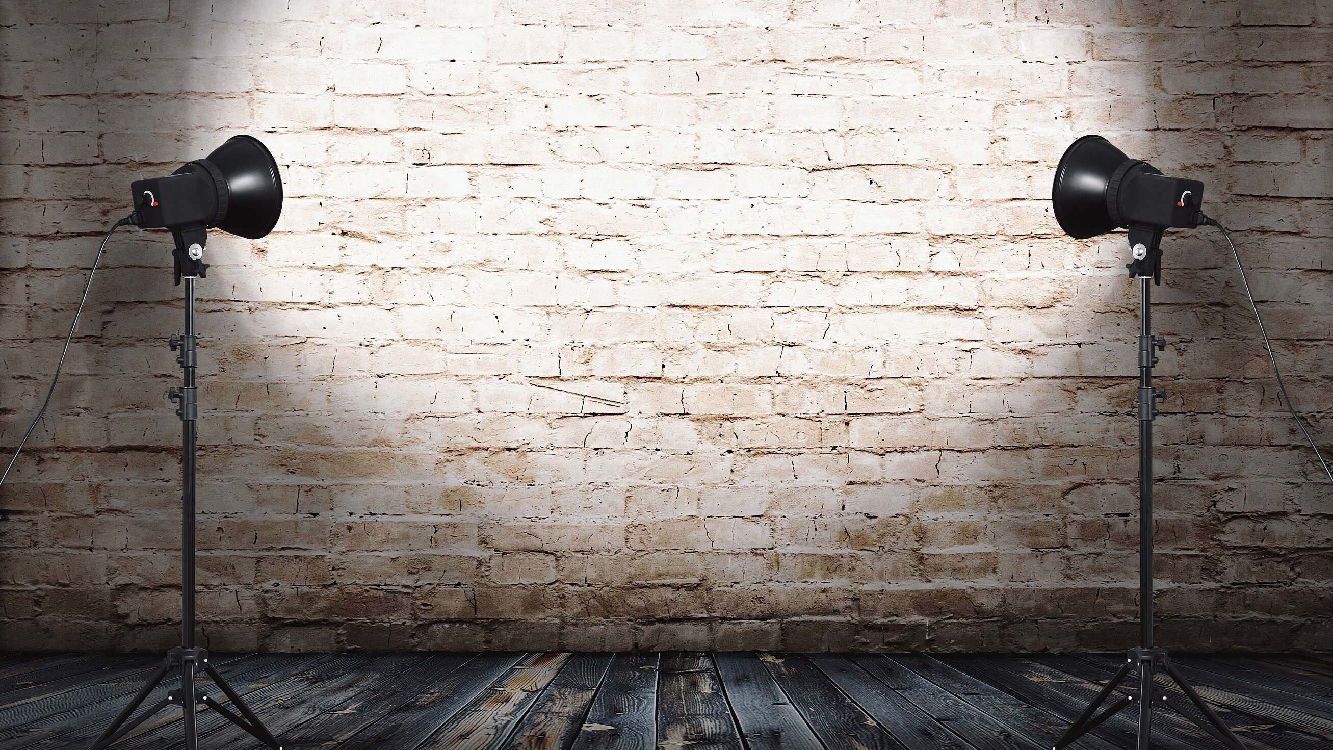 Two studio lights illuminating a brick wall in a photography studio.