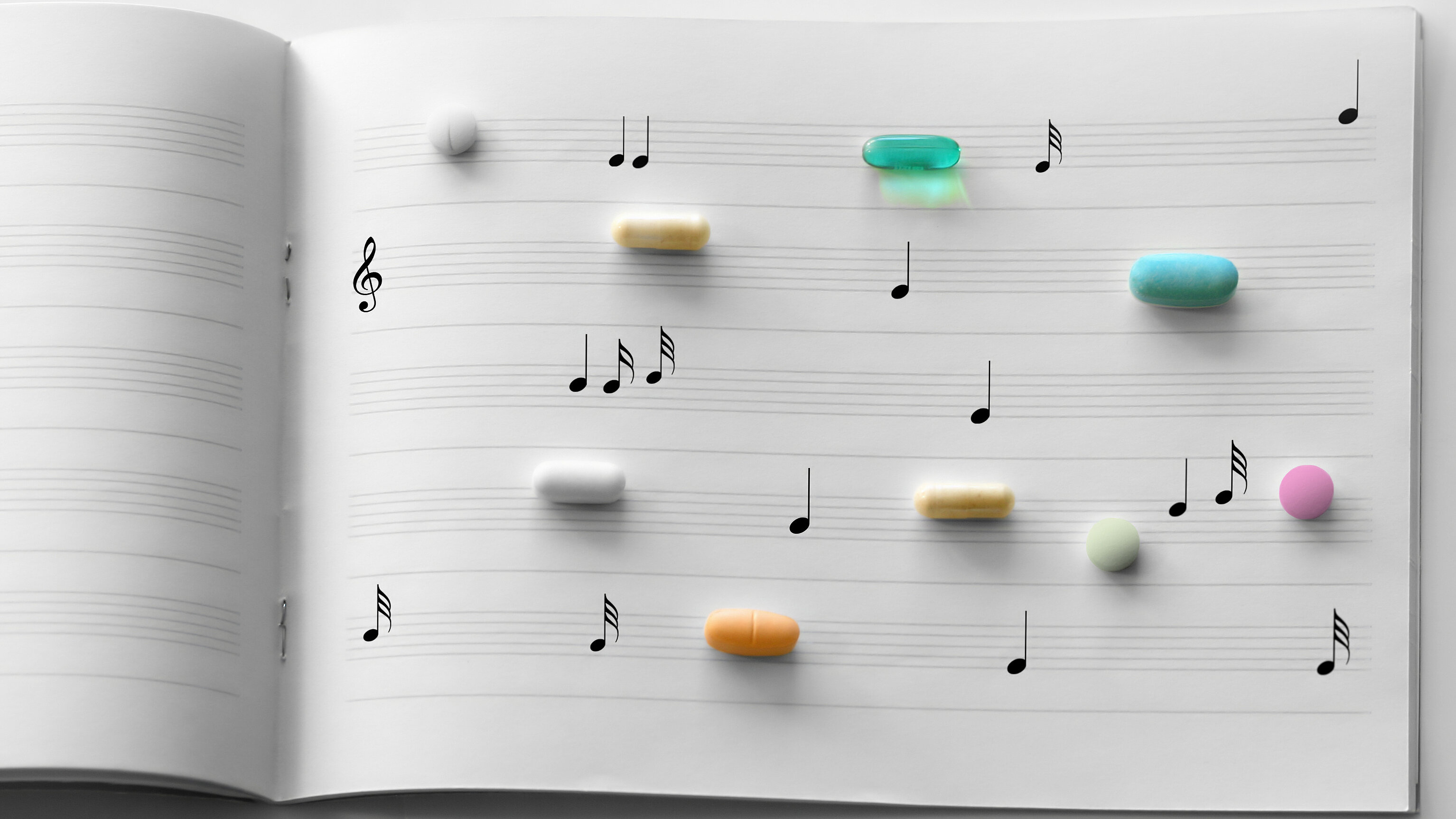 An open sheet music book displays musical notes on staff lines, with various colorful tablets and capsules placed across the pages. The medications are arranged like musical elements, illustrating a connection between music and medical treatment, such as in the context of music therapy or healthcare.